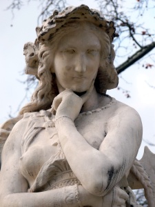 Photographie d'une statue représentant la prophétesse Velléda. Elle porte une sorte de tunique dévoilant sa poitrine et semble pensive, une main sous le menton