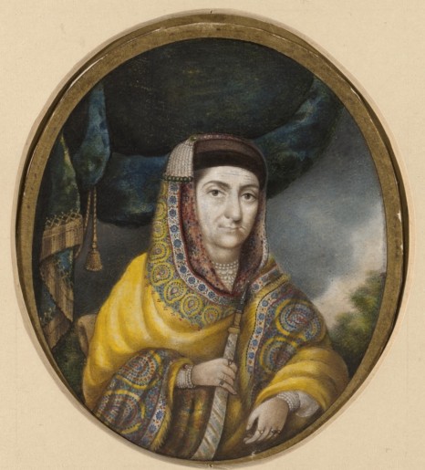 Cette image représente la Bégum Samru en habits moghols. Elle porte un manteau brodé de riches motifs et un voile sur ses cheveux, retenu par des rangs de perle. Elle tient un sabre à la main.