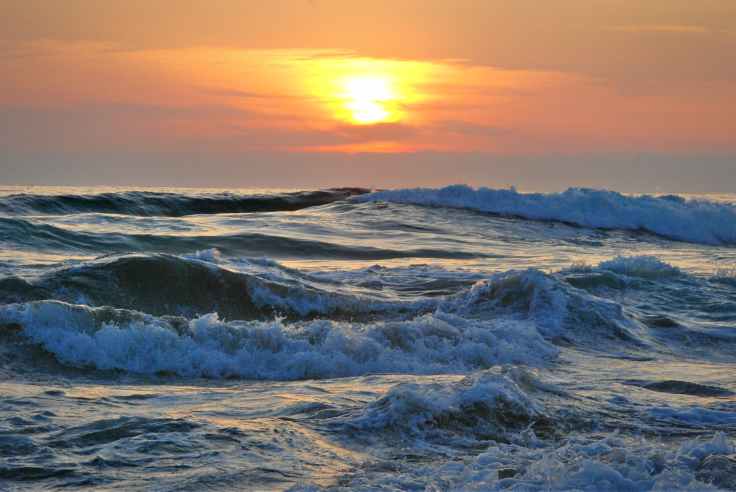 Photo d'un coucher du soleil sur l'océan, avec des vagues et de l'écume © Sascha Thiele